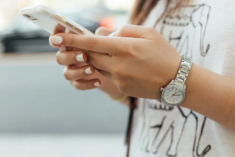 スマートフォンを両手で操作する女性の手元